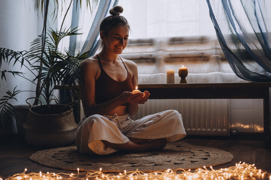 Woman sitting cross legged on floor holding a candle
