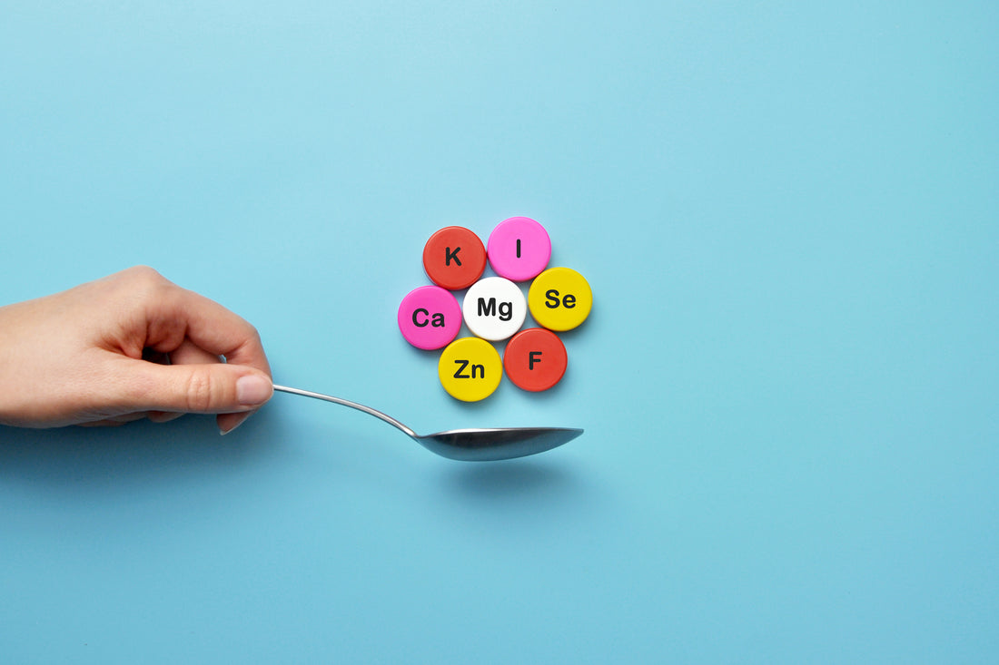 Colorful pills labeled with mineral elements like Magnesium, Zinc, and Selenium on a spoon, symbolizing the concept of mineral supplementation.