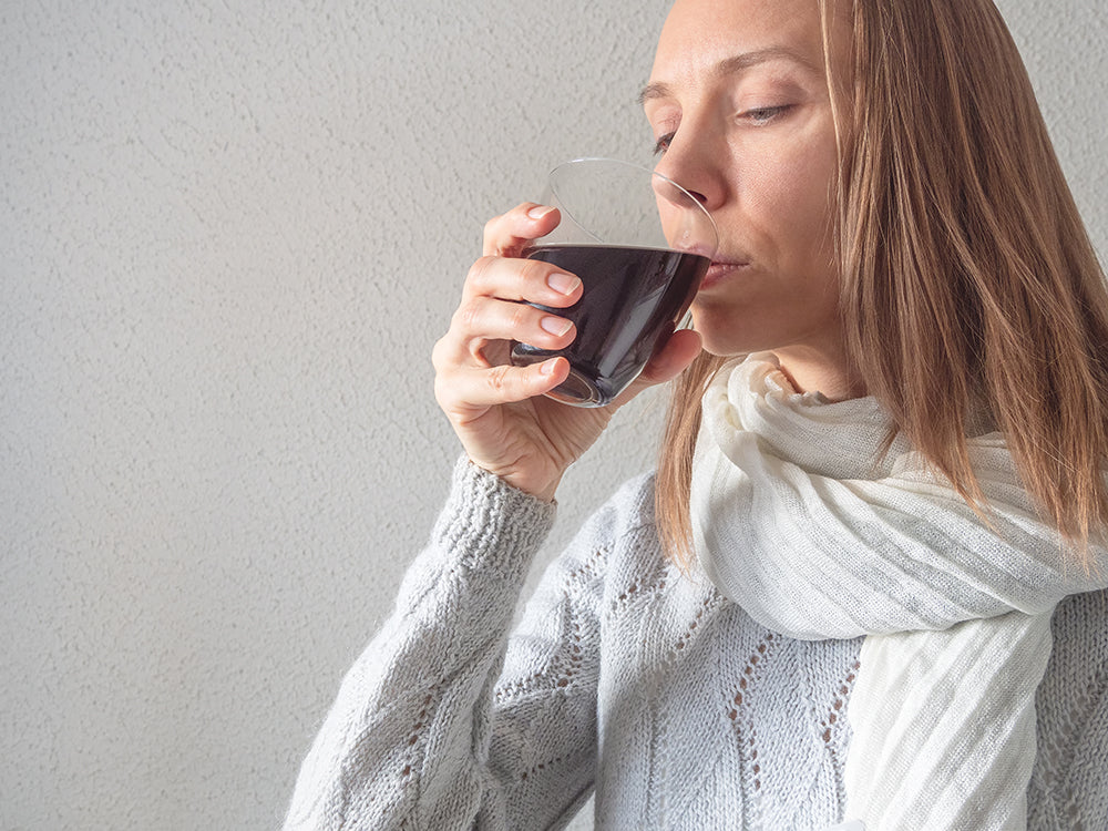  A woman sips a glass of water with Micro-BOOST, exemplifying the ease of incorporating humic substances into a daily routine to support the body's natural detoxification processes.