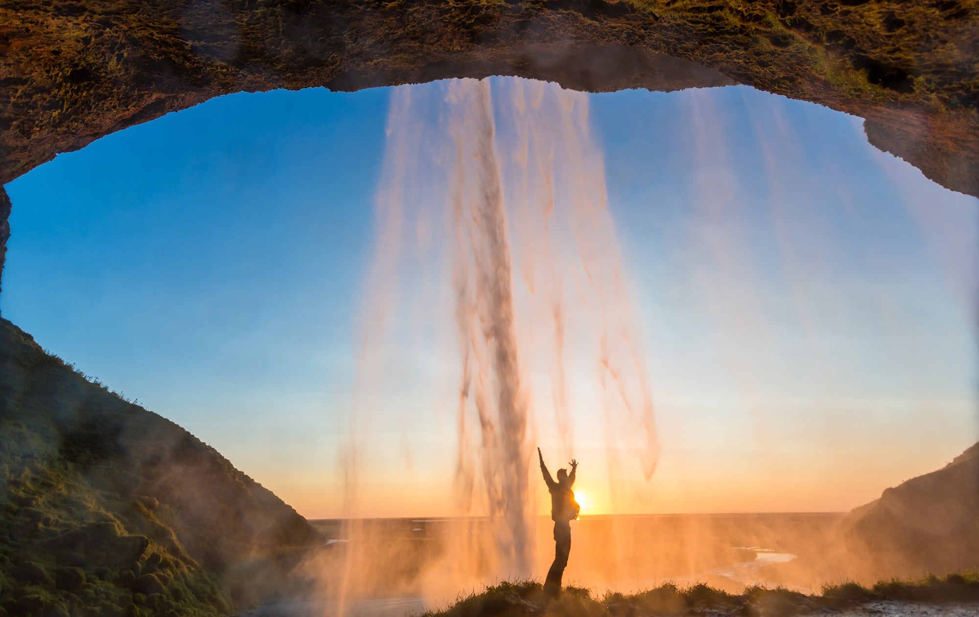 man standing under waterfall