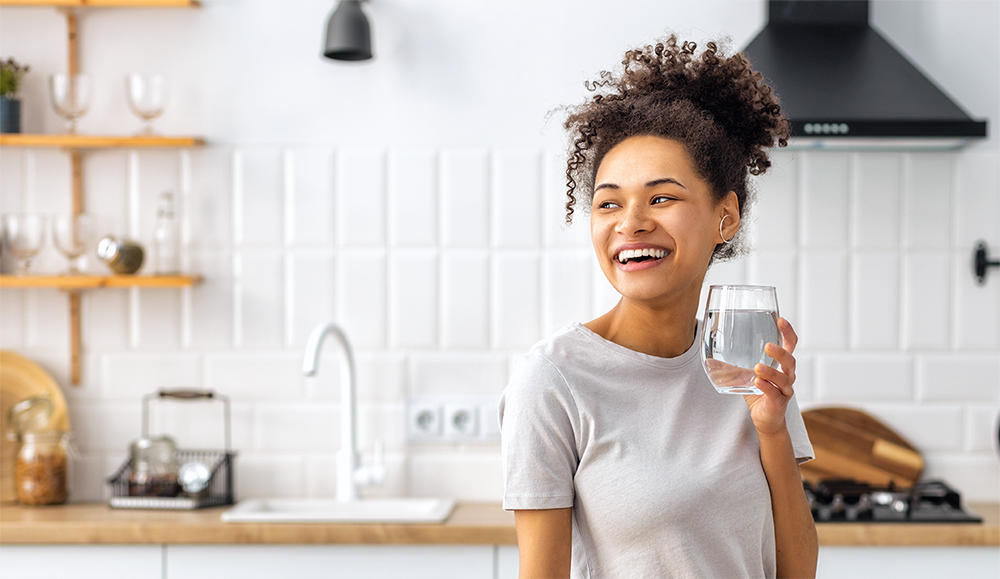 woman smiling drinking a glass of water