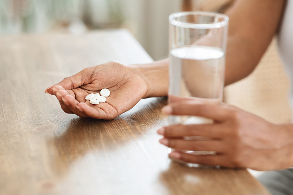 hand with tablets in them and a glass of water