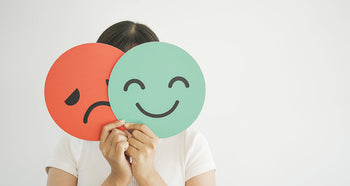 woman holding up happy and sad paper faces