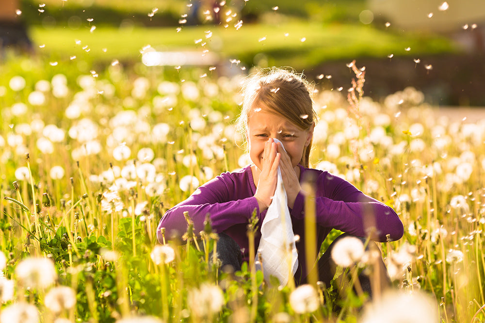 young girl in field of flowers having allergy attack