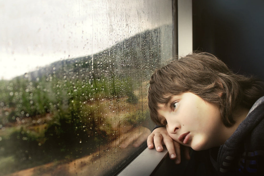 kid bored looking out of a rainy window