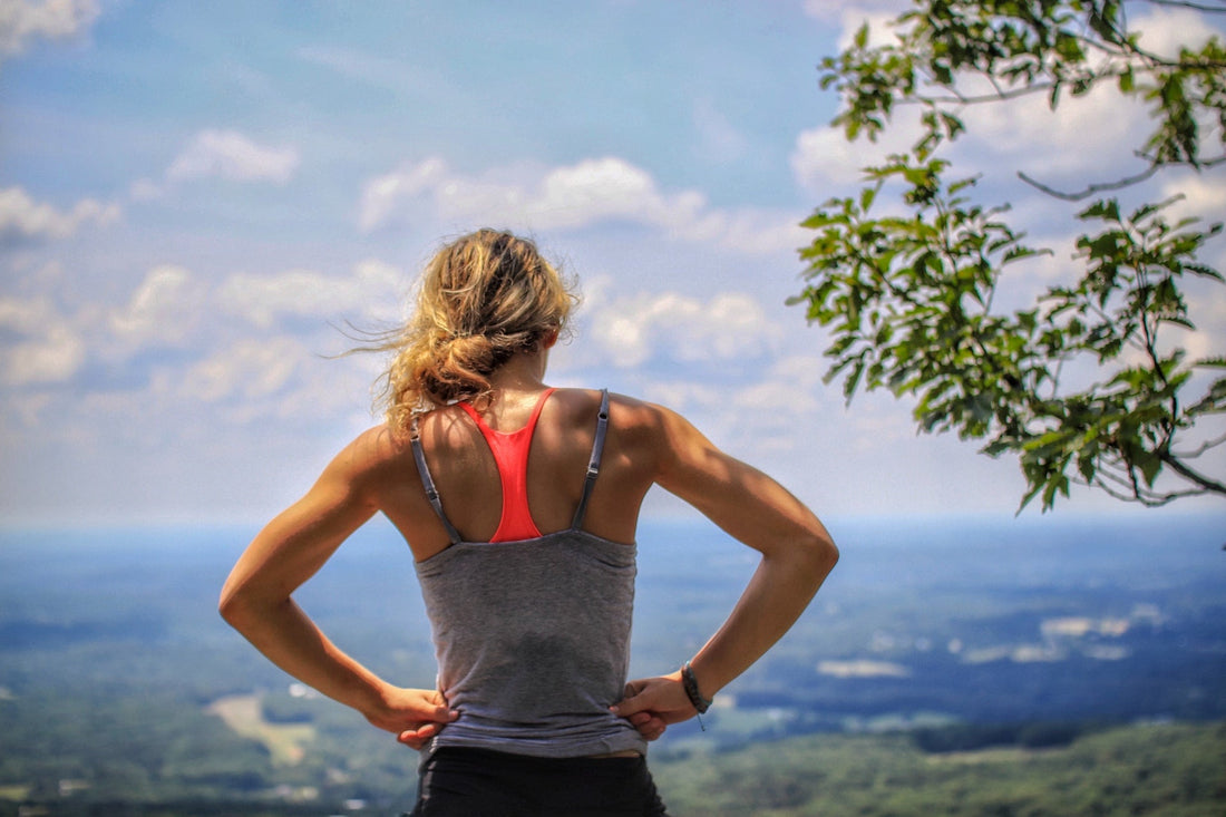 athletic woman standing at the top of mountain